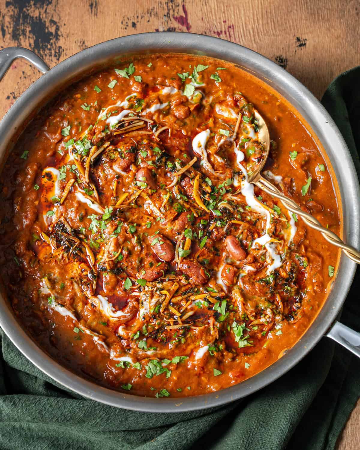 overhead view of rajma masala topped with yogurt, tadka and cilantro in a saucepan.