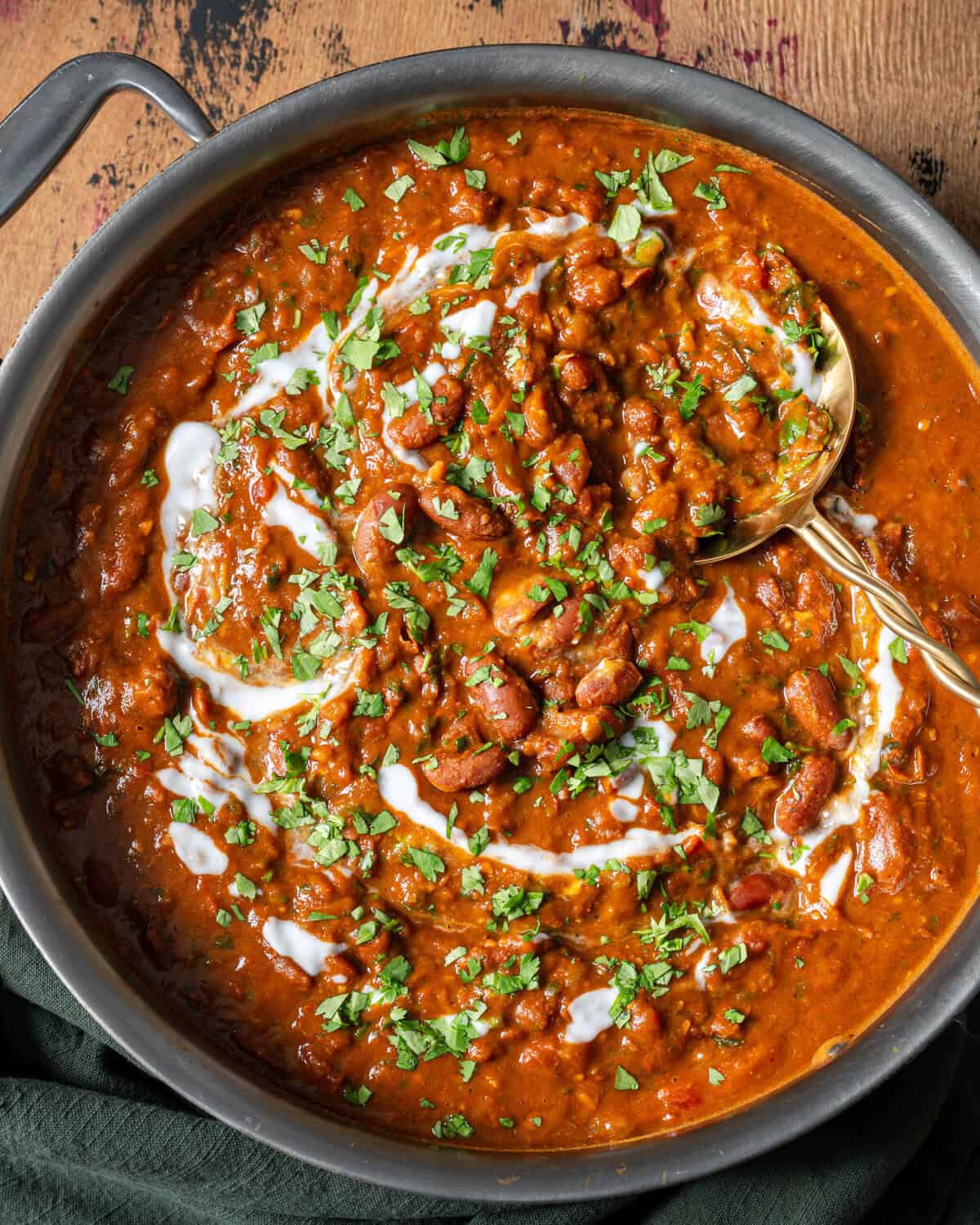 rajma masala topped with yogurt and cilantro in a deep saute pan.