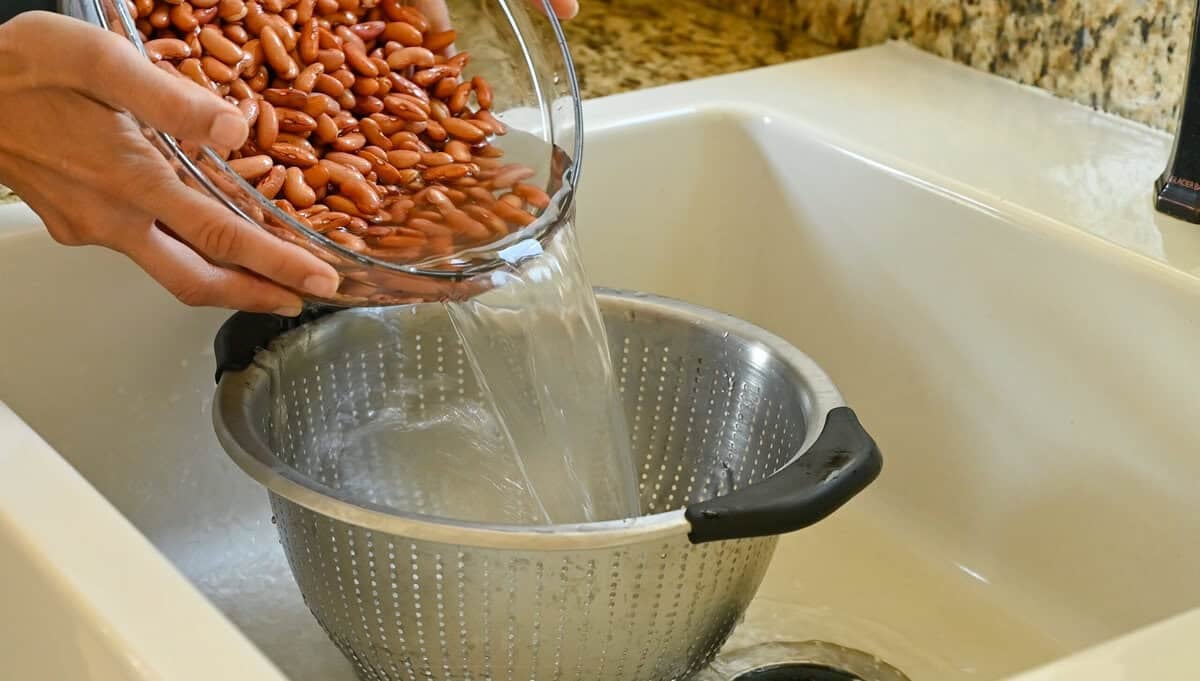 person draining soaked kidney beans in a colander.