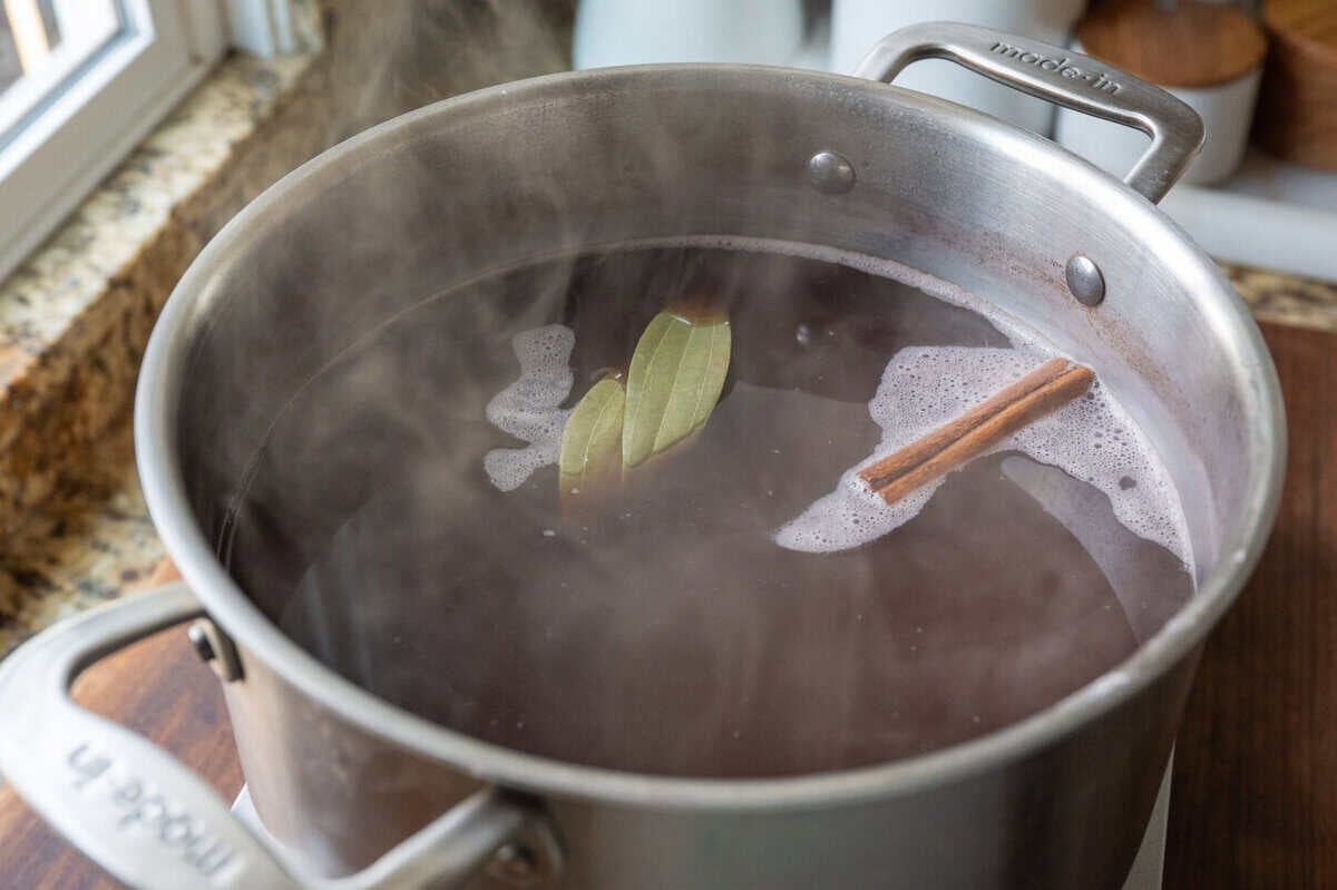 cooked beans, water, salt, cinnamon stick and bay leaves in a pot.