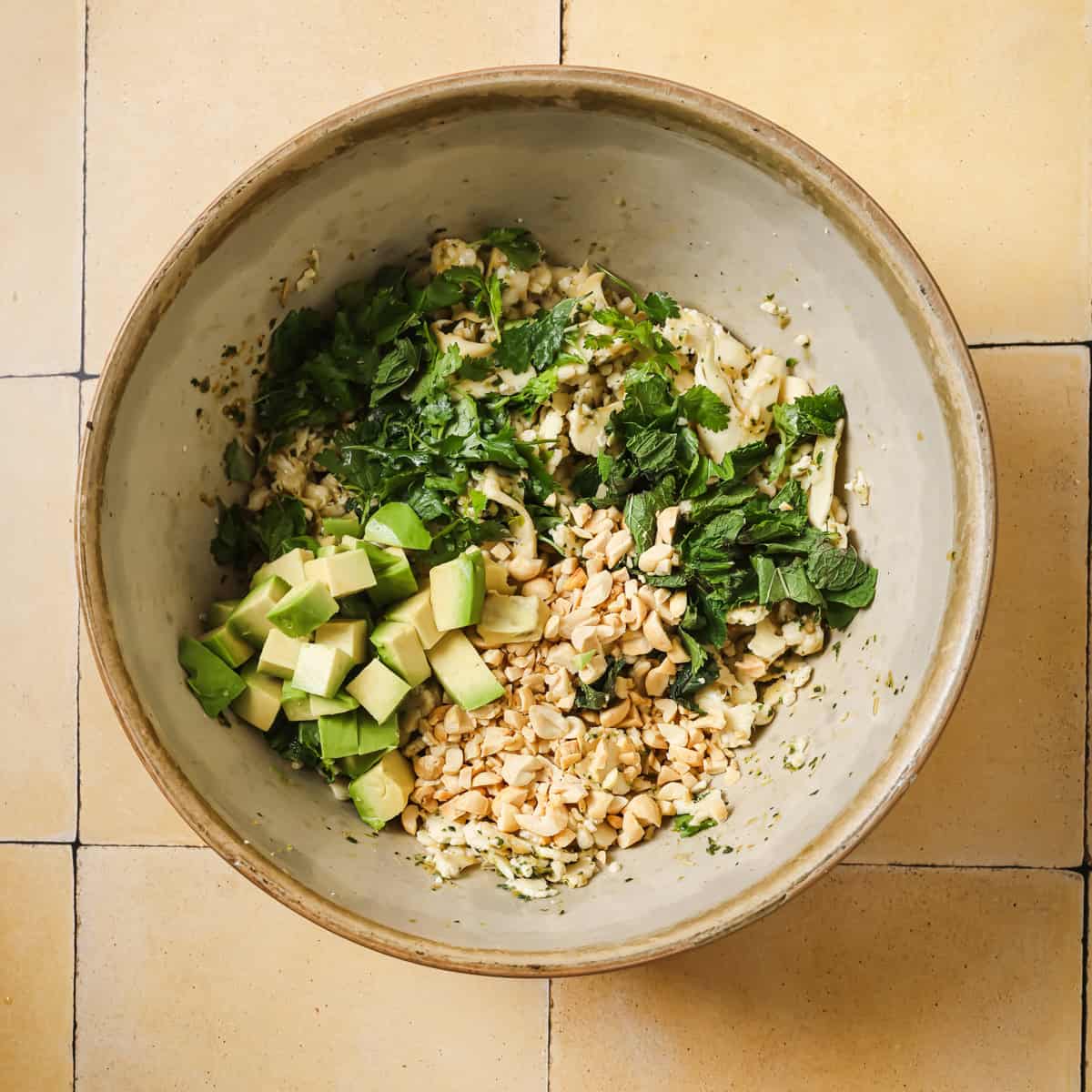 mint, cilantro, peanuts and avocado added to the bowl of dressed cauliflower.