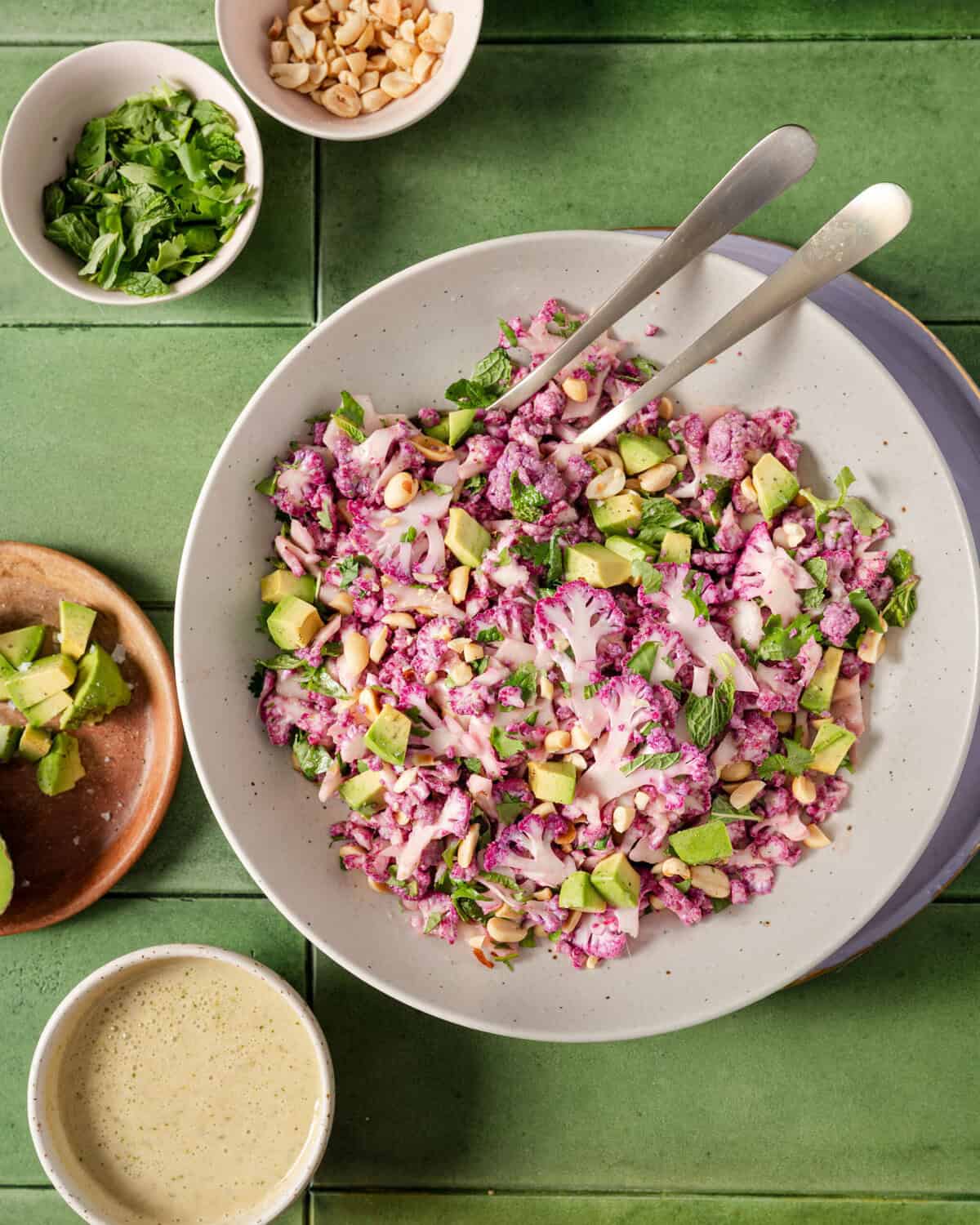 bowl of cauliflower salad next to various small ingredient bowls.