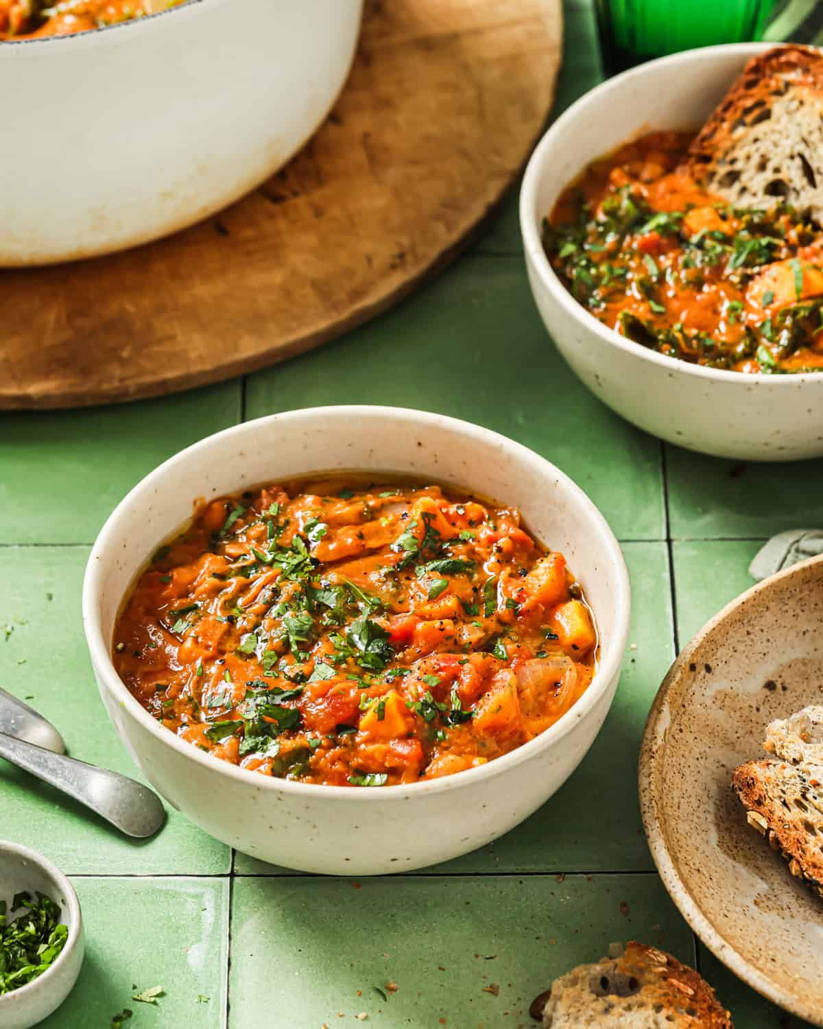 two bowls of domoda with a side of crusty bread on a table.