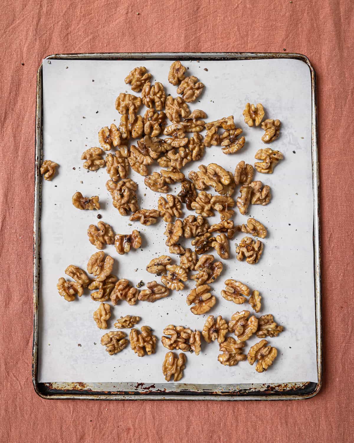 raw walnuts on a parchment paper lined baking sheet.