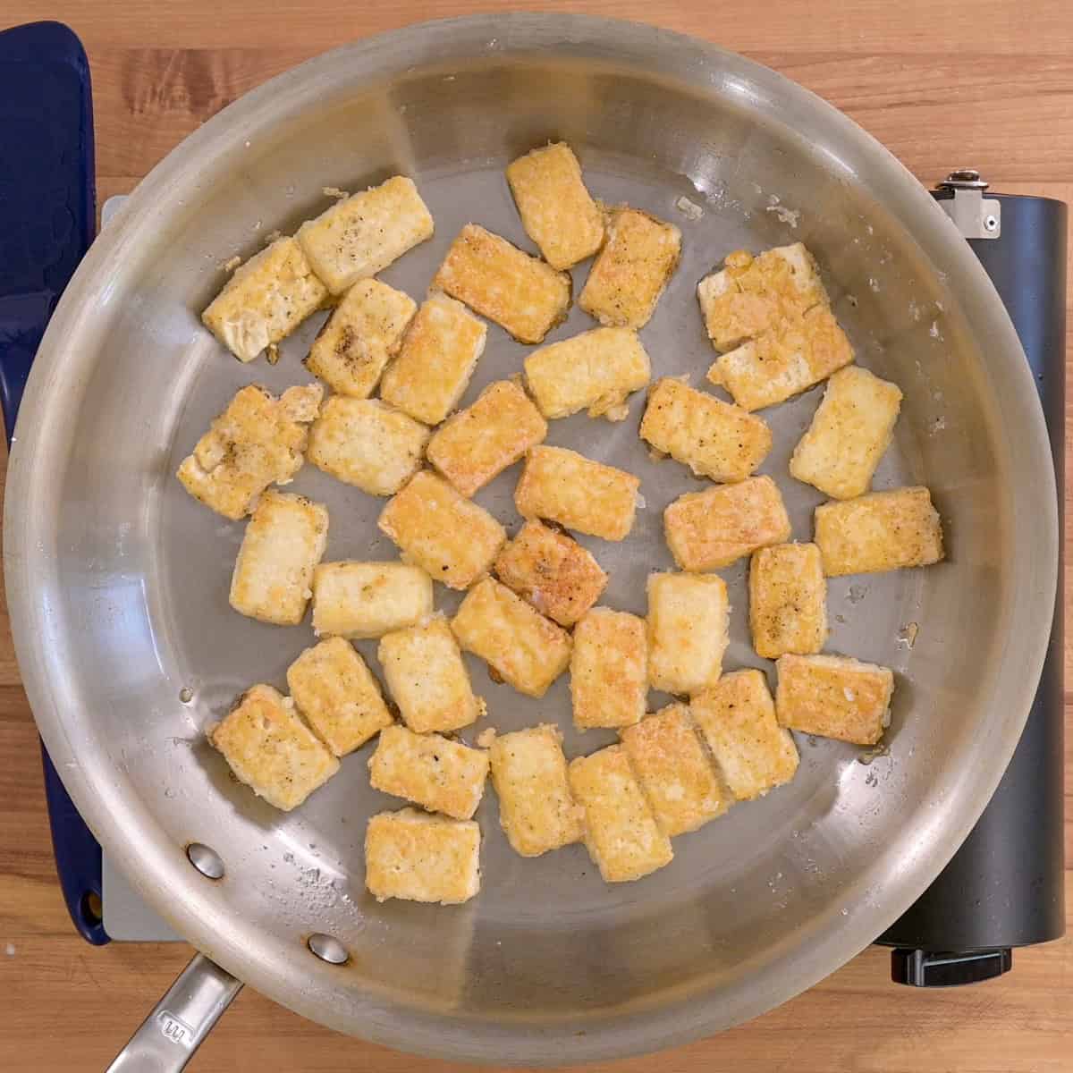 Tofu pieces in a frying pan after being cooked.