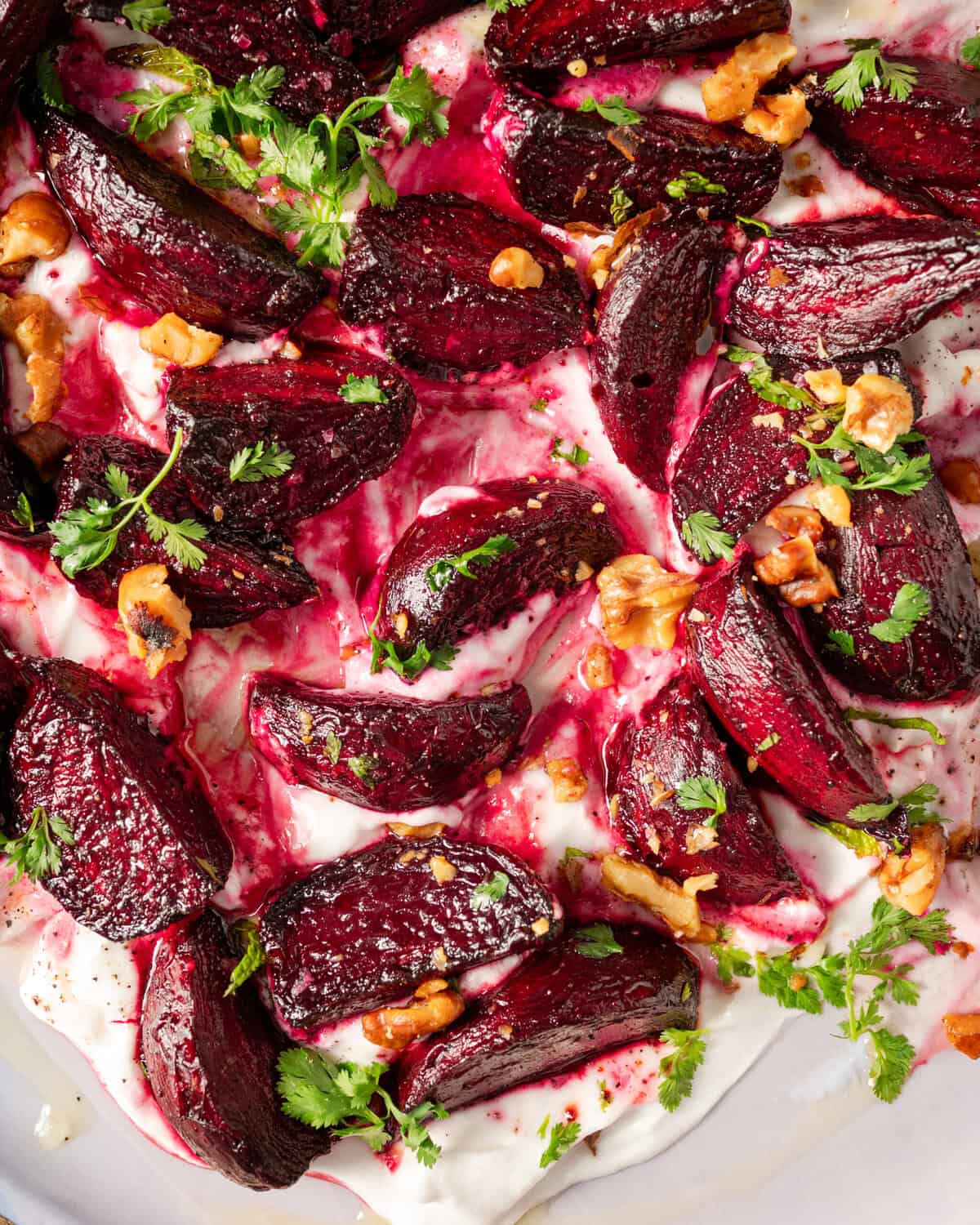close up of yogurt topped with roasted beets, roasted walnuts and chopped parsley.