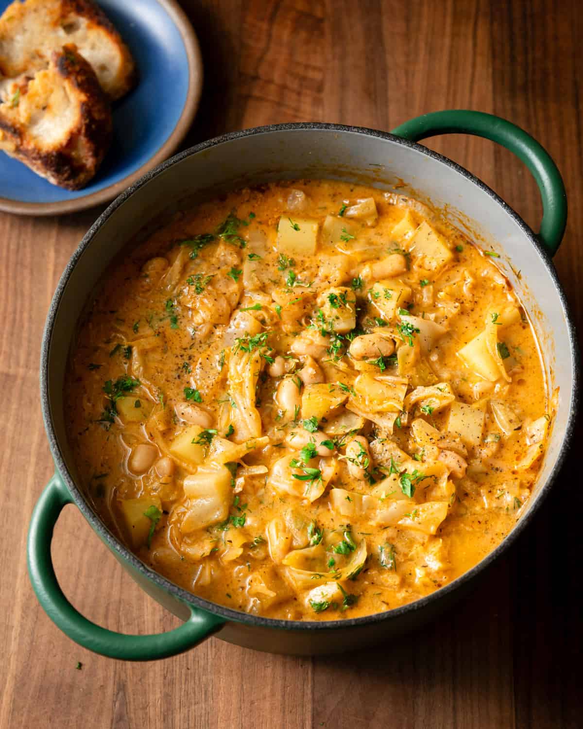 overhead shot of golden cabbage soup in a pot on a table.