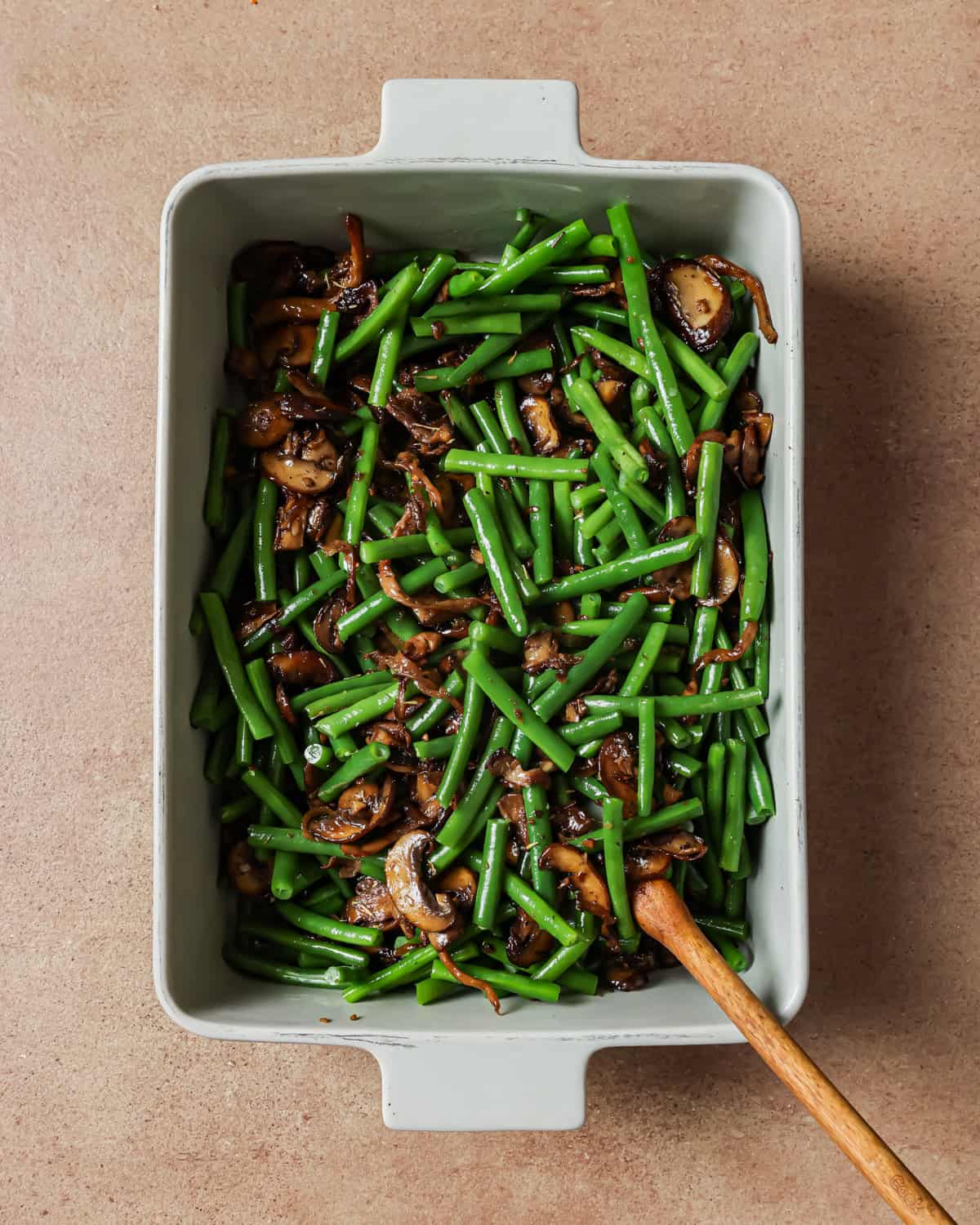 cooked mushroom mixture added to green beans in the baking dish.
