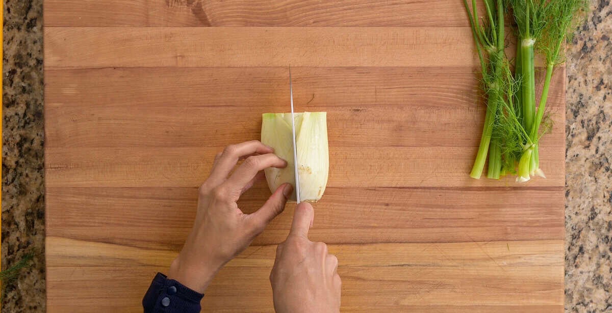 person cutting fennel bulb in half.
