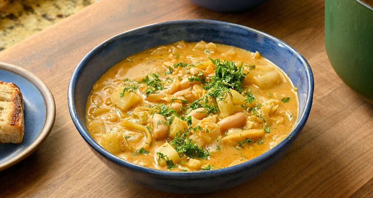 finished golden cabbage soup in a bowl topped with the herb topping.