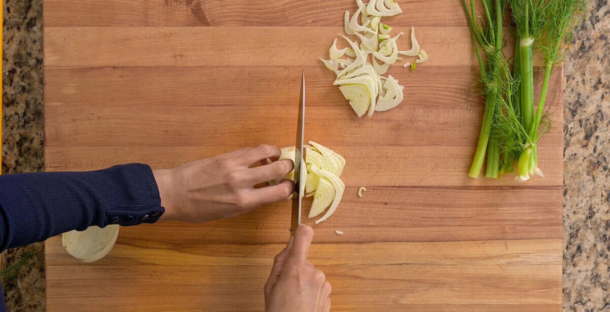 person slicing fennel bulb.